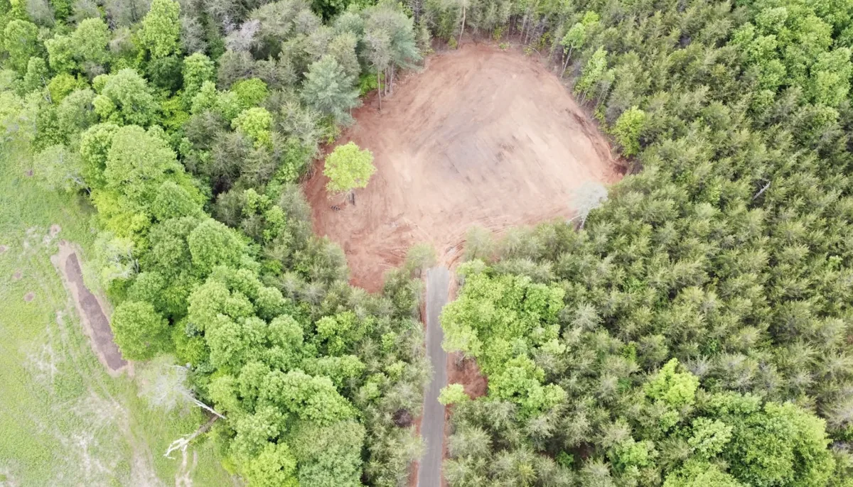 Aerial view of a finished cleared and graded home site surrounded by forest with a new access drive β Platinum Construction & Crane, Hickory NC
