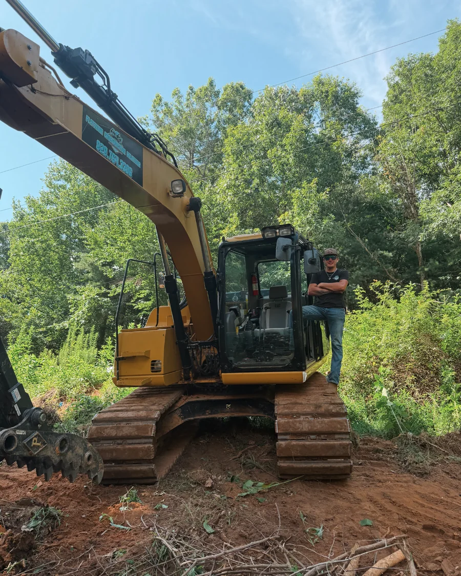 Chandler Shuffler, owner and operator of Platinum Construction & Crane, standing on his excavator at a Hickory-area job site